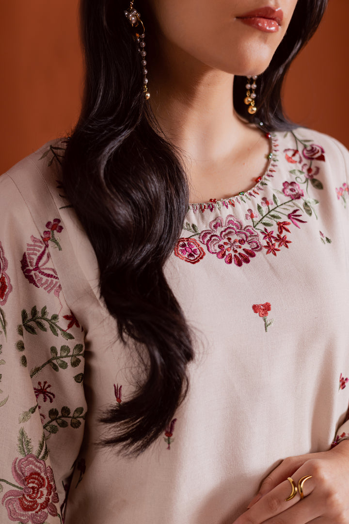 Delicate floral embroidery in soft pink and green tones on a beige khaddar base. A graceful Pakistani ready-to-wear outfit ideal for festive occasions and timeless everyday style