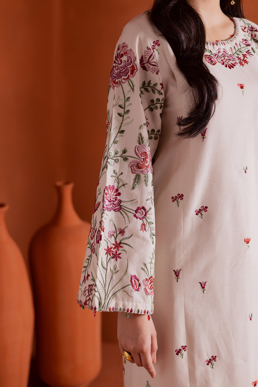 Detailed sleeve embroidery on beige khaddar shirt with floral design. Elegant South Asian outfit blending comfort and luxury.