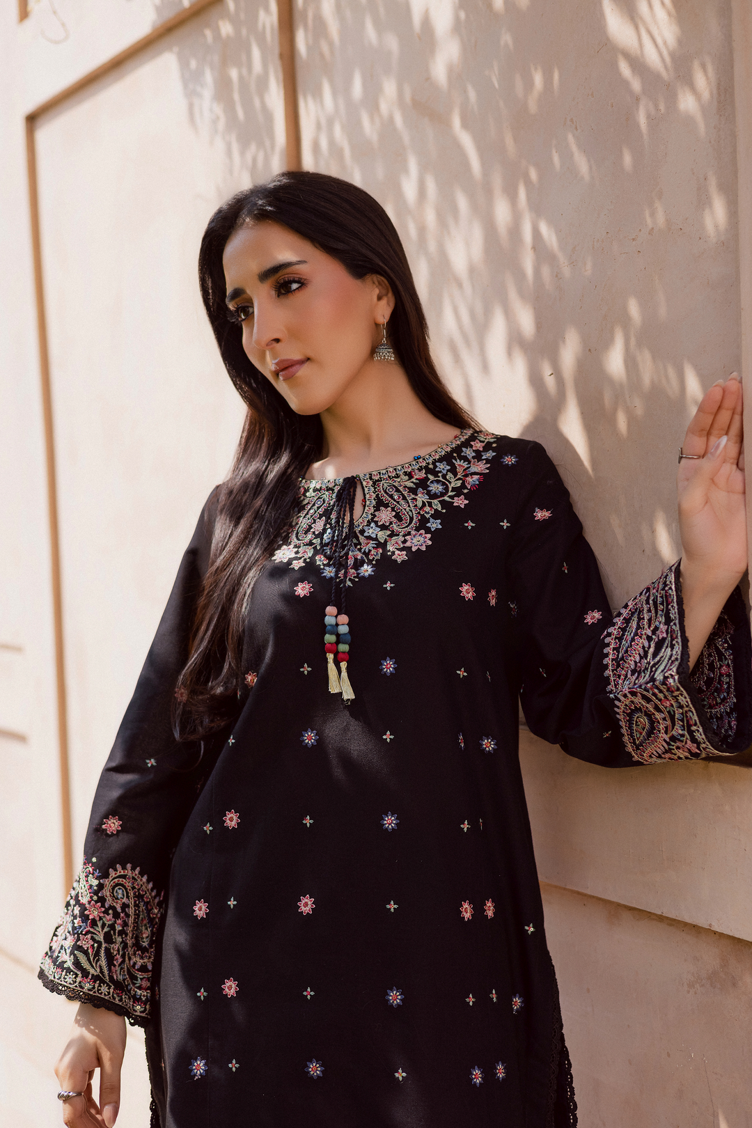 Close-up of black embroidered kurta for women featuring intricate multicolor embroidery on neckline and cuffs, paired with statement earrings. Traditional Pakistani outfit ideal for festive or everyday wear