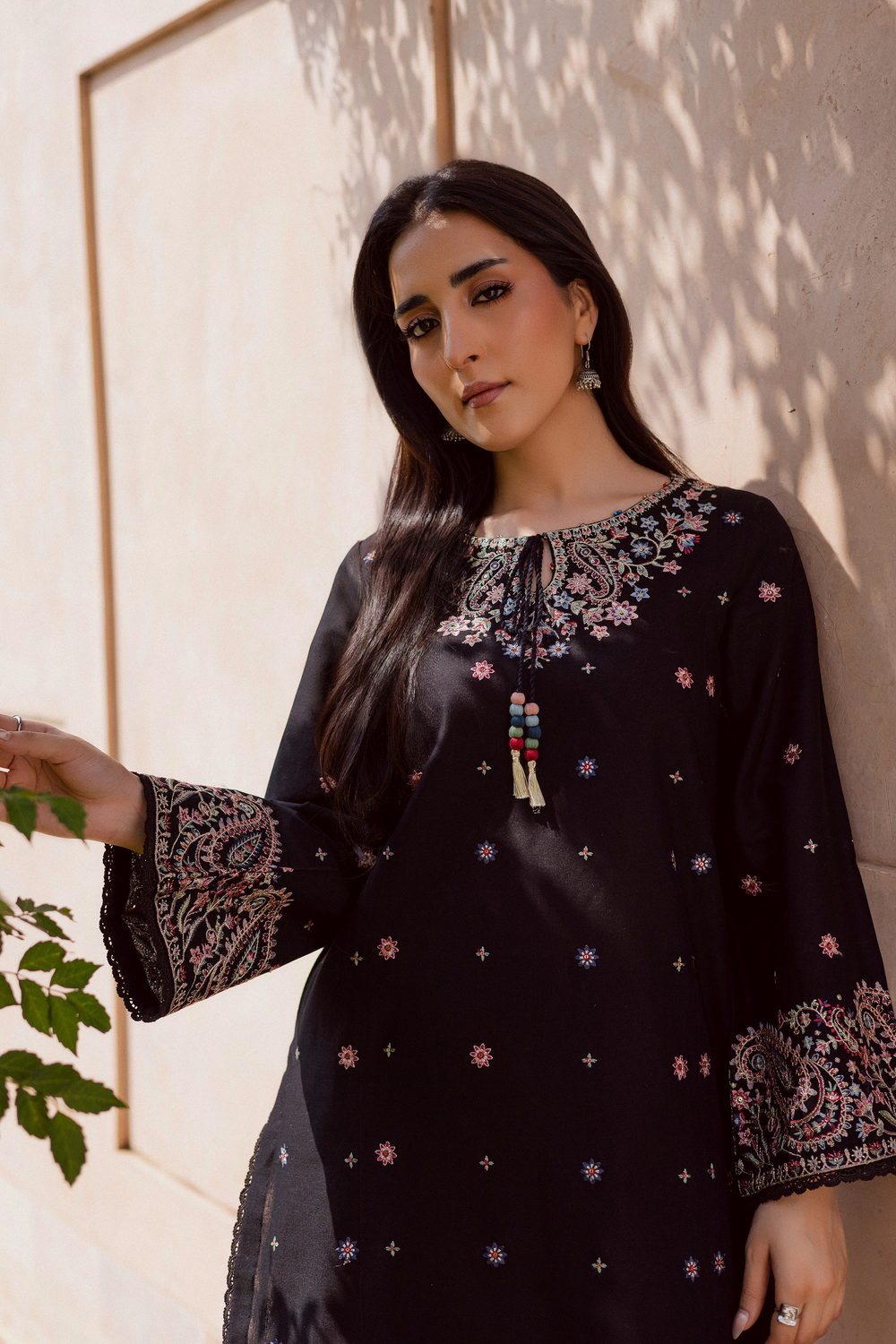 Black embroidered kurta for women featuring intricate multicolor floral embroidery on neck and cuffs, styled with statement earrings. Pakistani traditional outfit for festive, party, or everyday wear