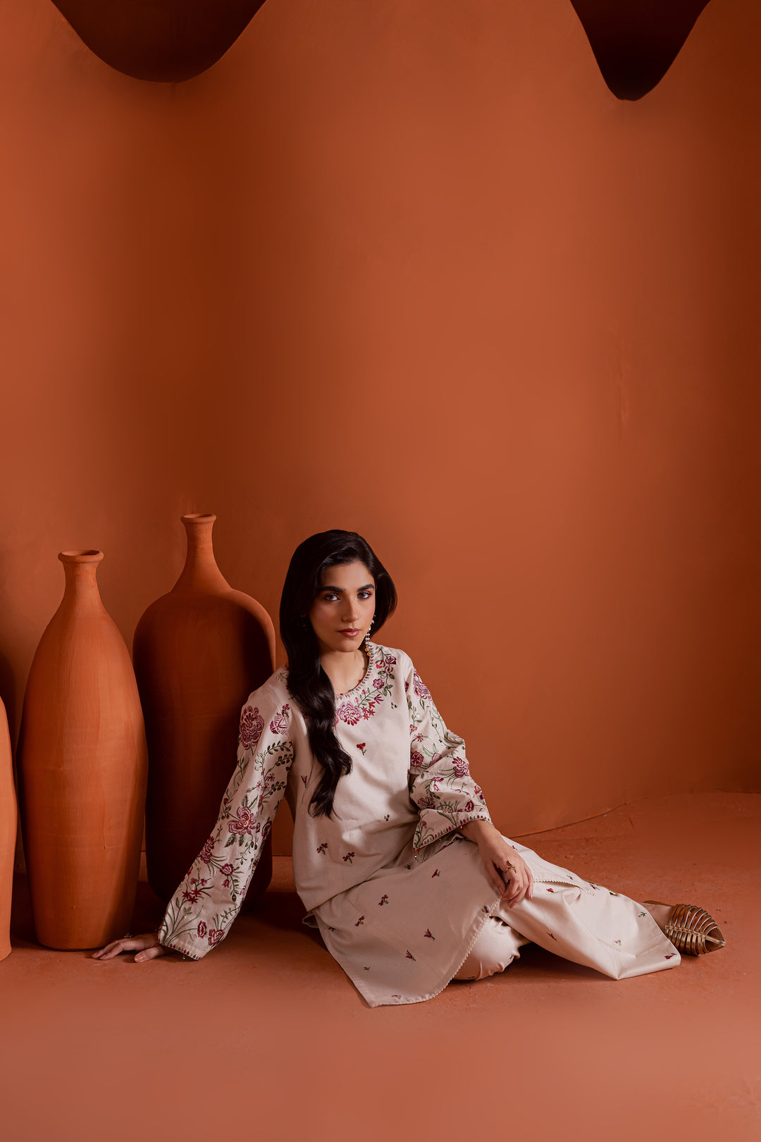 Seated model wearing beige embroidered khaddar 2 piece outfit. Ideal for festive wear, elegant lunches, or cultural events