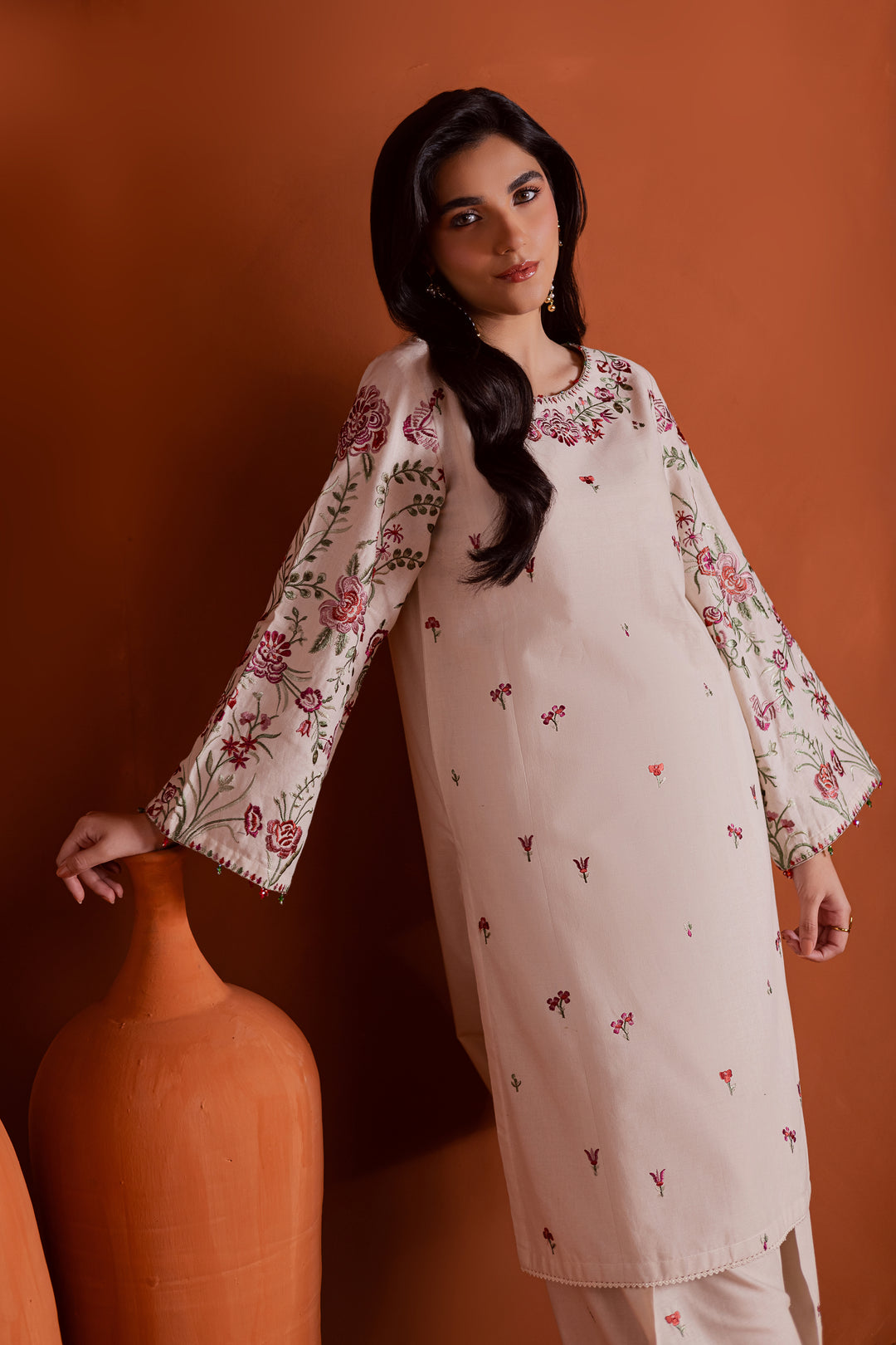 Close up of pink and green floral embroidery on beige khaddar shirt neckline. Beautiful craftsmanship and soft fabric texture