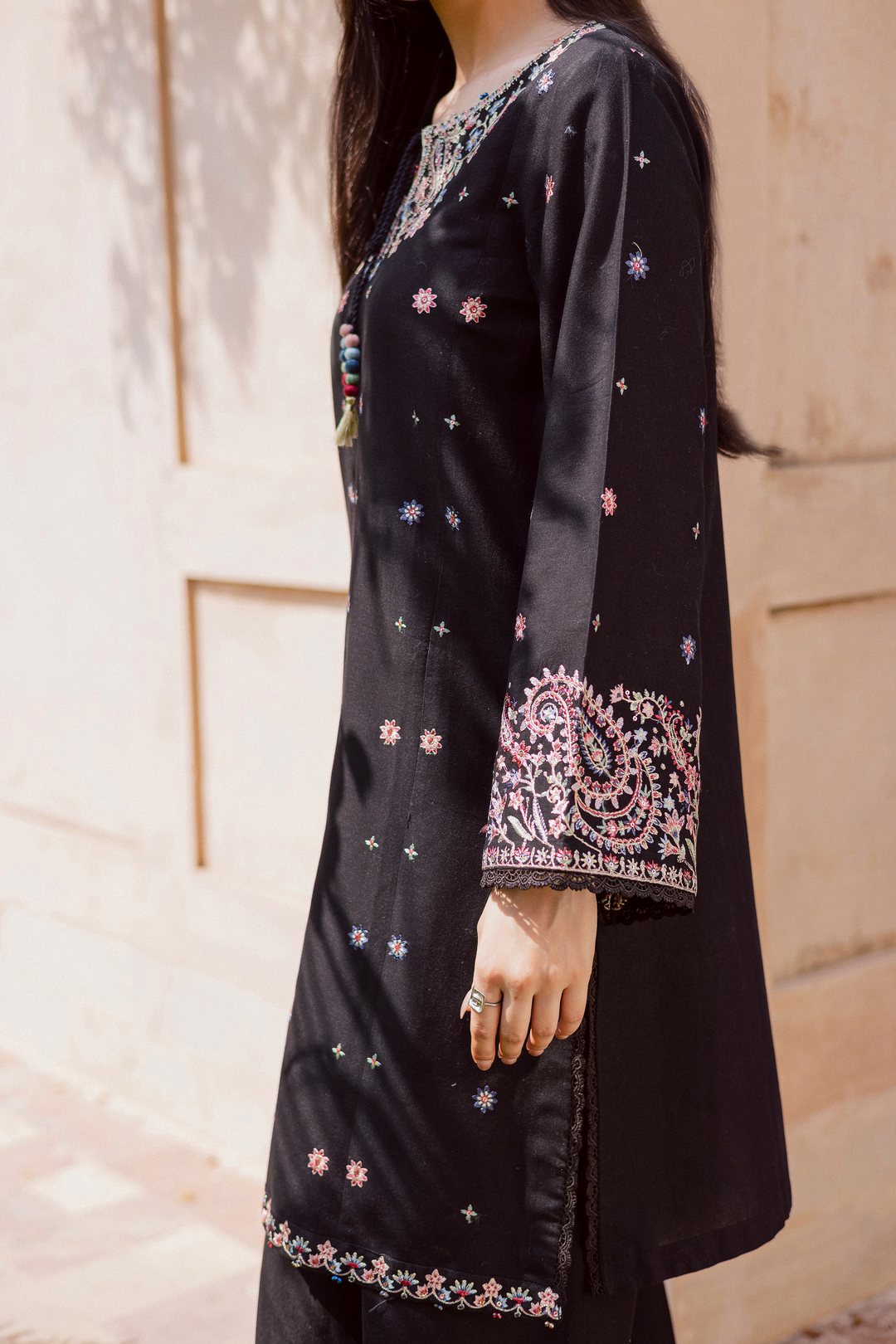 Black khaddar kurta with intricate multicolor embroidery on sleeves and hem, featuring paisley patterns and lace finishing. A timeless Pakistani outfit for women, perfect for festive or casual wear