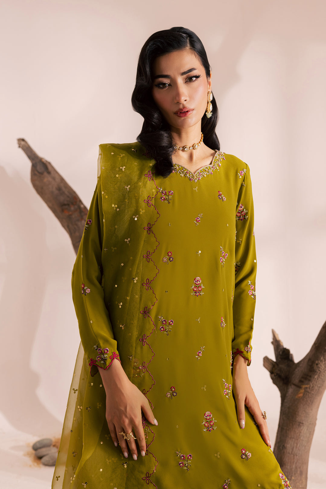 Pakistani woman wearing an olive green embroidered festive outfit with wide-leg trousers and chiffon dupatta. South Asian ready-to-wear suit blending elegance and comfort, available globally from Batik
