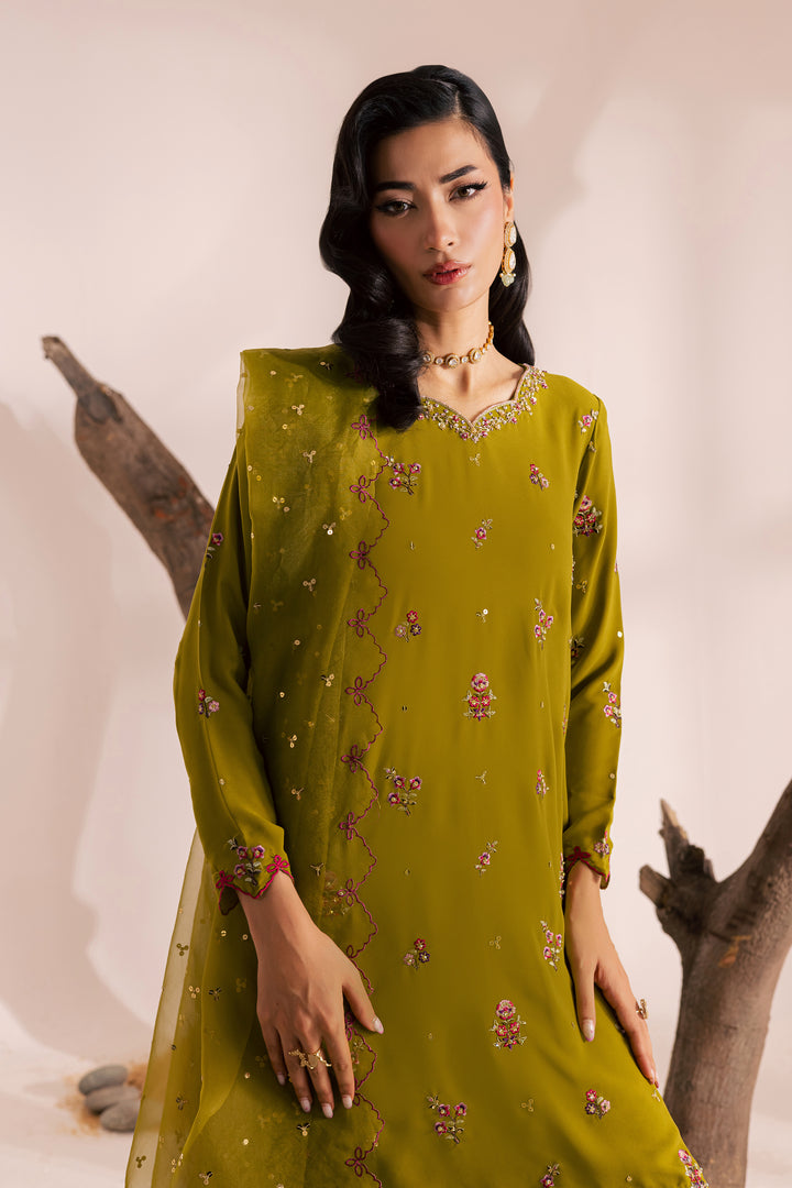Pakistani woman wearing an olive green embroidered festive outfit with wide-leg trousers and chiffon dupatta. South Asian ready-to-wear suit blending elegance and comfort, available globally from Batik