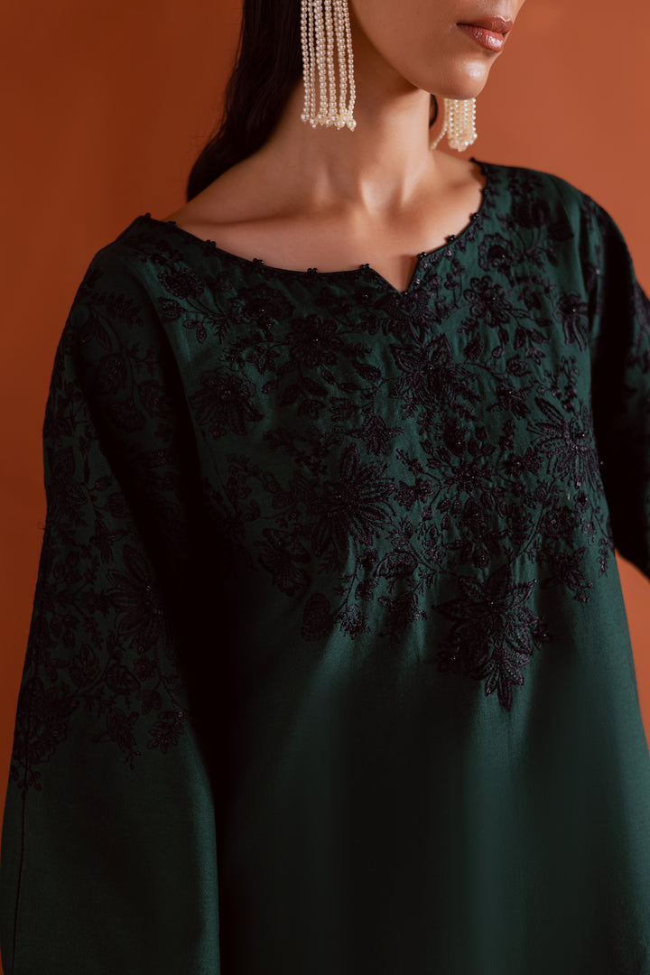 Close-up of detailed sleeve embroidery on emerald green khaddar shirt - handcrafted embellishments with artistic black threadwork