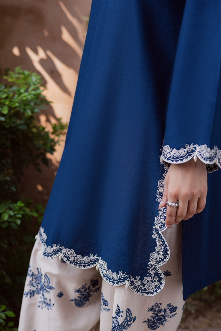 Indian Batik UAE two piece khaddar set featuring a short straight embroidered shirt with scalloped borders keyhole neckline and pearl embellished sleeves paired with a fully embroidered contrasting shalwar. Affordable ethnic South Asian Desi Indian Pakistani designer wear UAE fashion for teens adults girls and women available in sizes XS S M L XL blue white trim