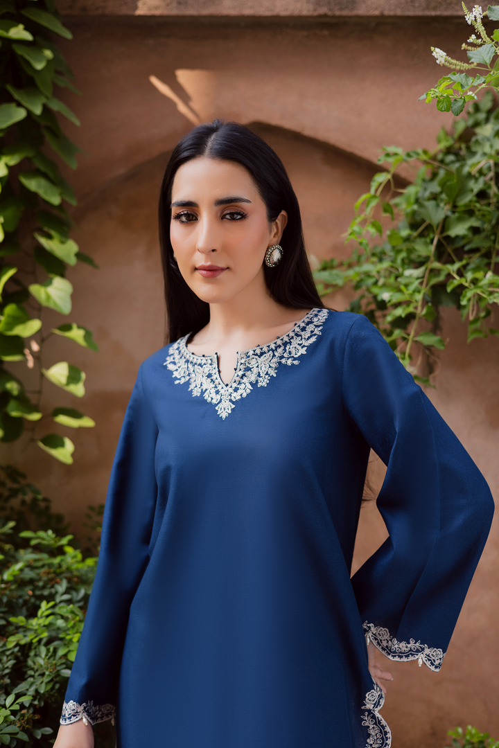 Indian Batik UAE two piece khaddar set featuring a short straight embroidered shirt with scalloped borders keyhole neckline and pearl embellished sleeves paired with a fully embroidered contrasting shalwar. Affordable ethnic South Asian Desi Indian Pakistani designer wear UAE fashion for teens adults girls and women available in sizes XS S M L XL blue white