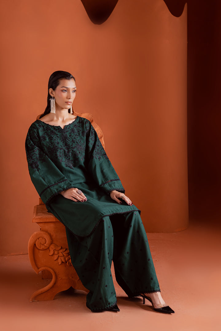 Model seated in emerald green embroidered khaddar outfit - luxurious ready-to-wear 2-piece Pakistani suit for Eid, weddings, and cultural events