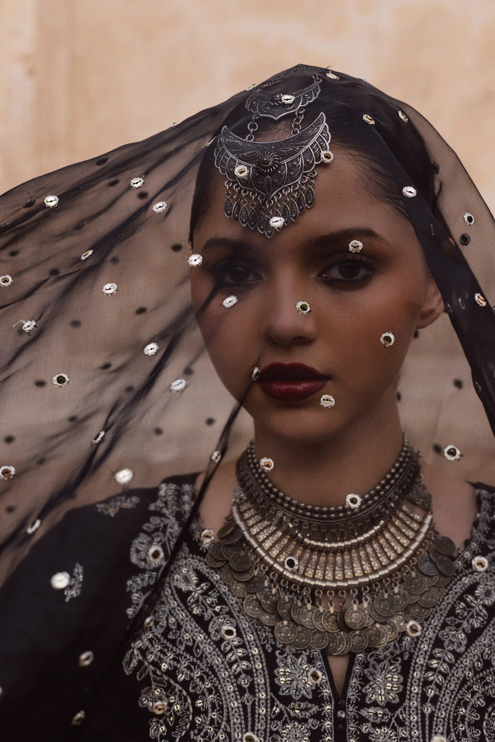 Batik UAE Arbish three piece black raw silk set featuring an embroidered paneled short shirt with crystal detailing paired with an embroidered raw silk sharara and organza dupatta. Affordable ethnic South Asian Desi Indian Pakistani designer wear UAE fashion for teens adults girls and women available in sizes XS S M L XL.