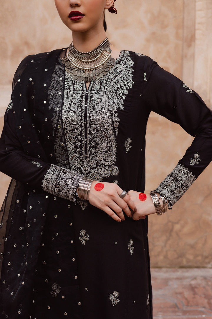 Batik UAE Arbish three piece black raw silk set featuring an embroidered paneled short shirt with crystal detailing paired with an embroidered raw silk sharara and organza dupatta. Affordable ethnic South Asian Desi Indian Pakistani designer wear UAE fashion for teens adults girls and women available in sizes XS S M L XL.