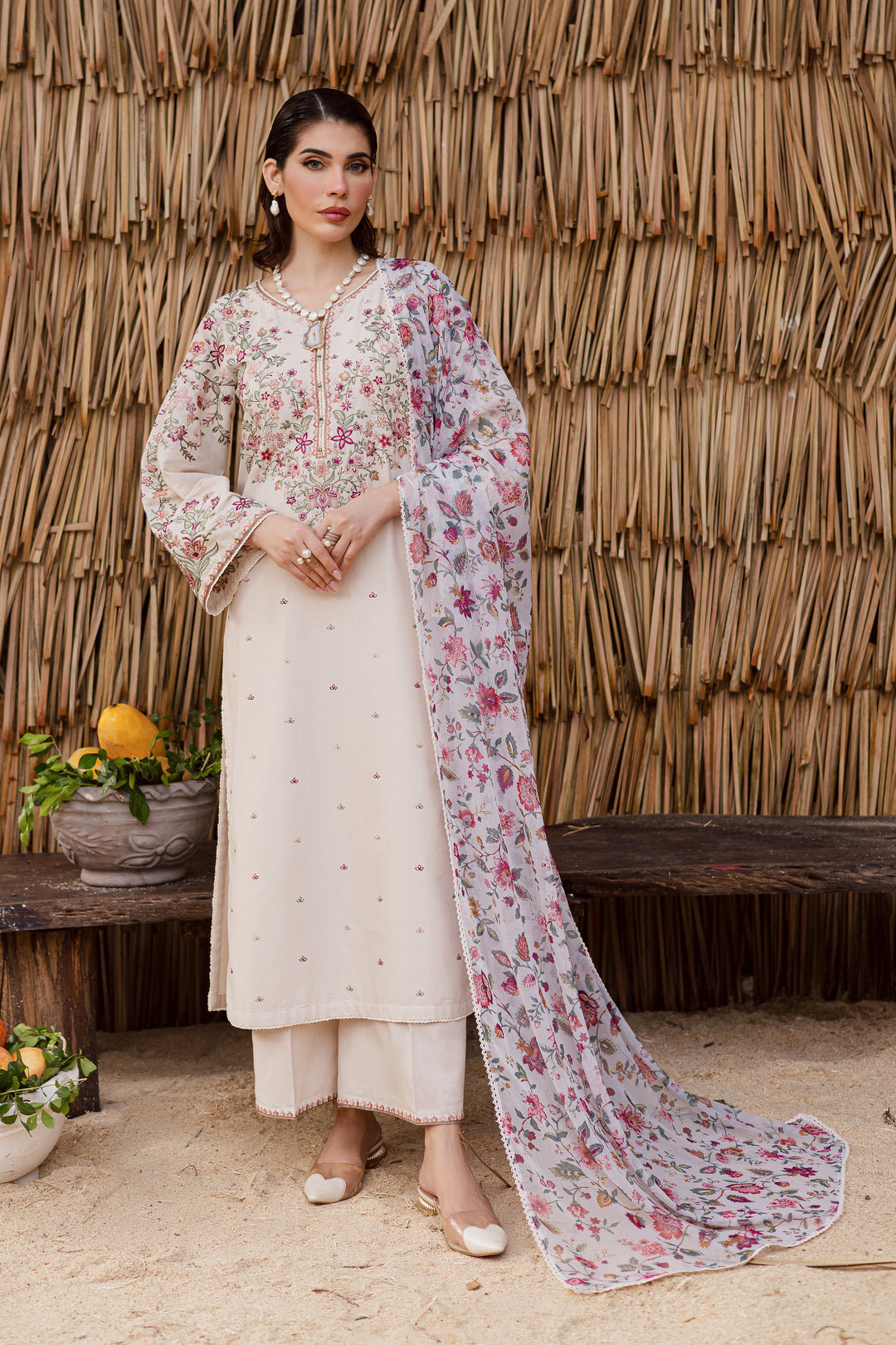 Beige khaddar 3-piece Pakistani dress with intricate embroidery and beaded neckline, paired with a floral printed dupatta. Perfect for festive wear and elegant occasions.