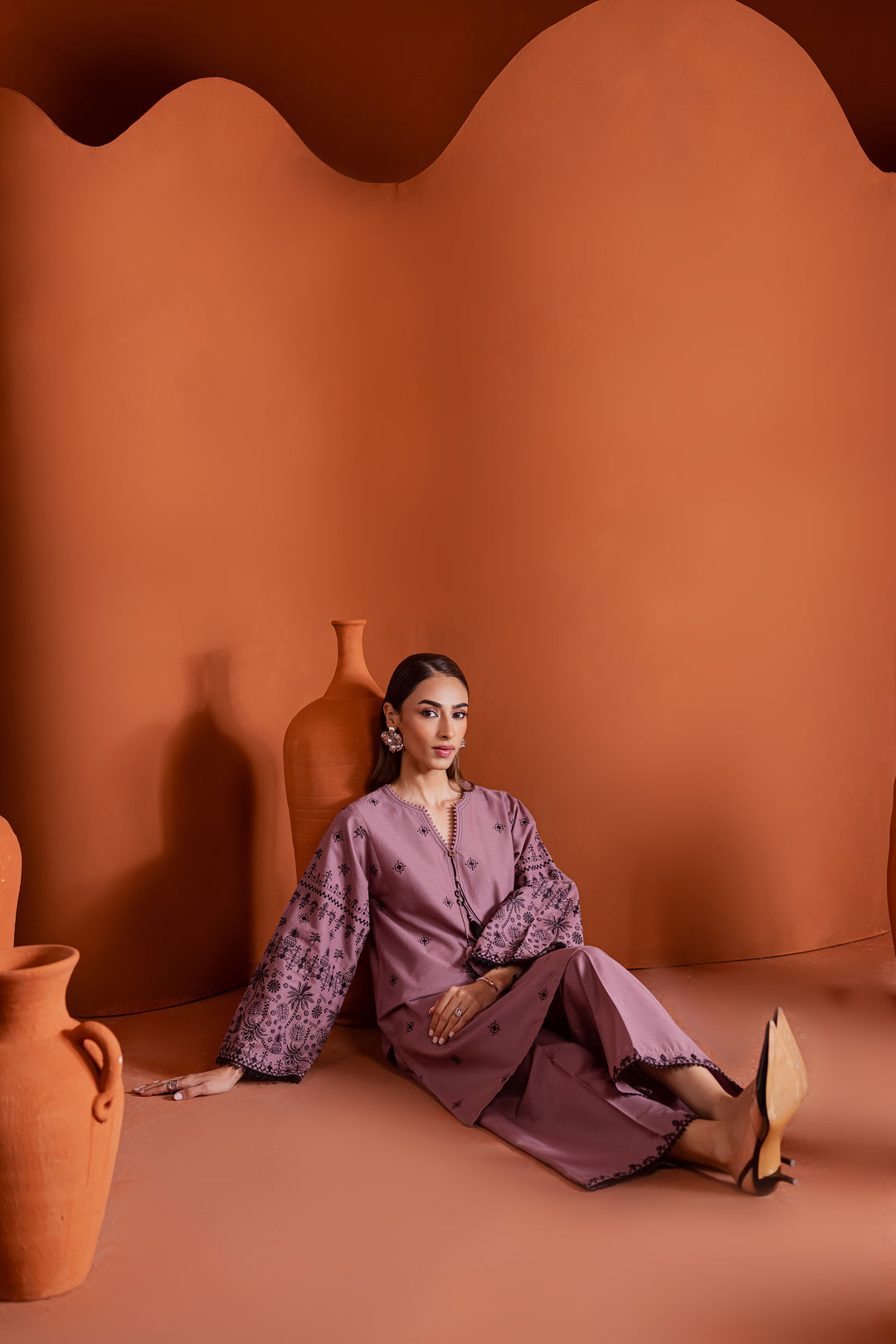 Model showcasing a modern Pakistani 2-piece khaddar outfit in onion pink with detailed embroidery and flared sleeves. A timeless blend of traditional craftsmanship and contemporary design for women across UAE, US, and beyond