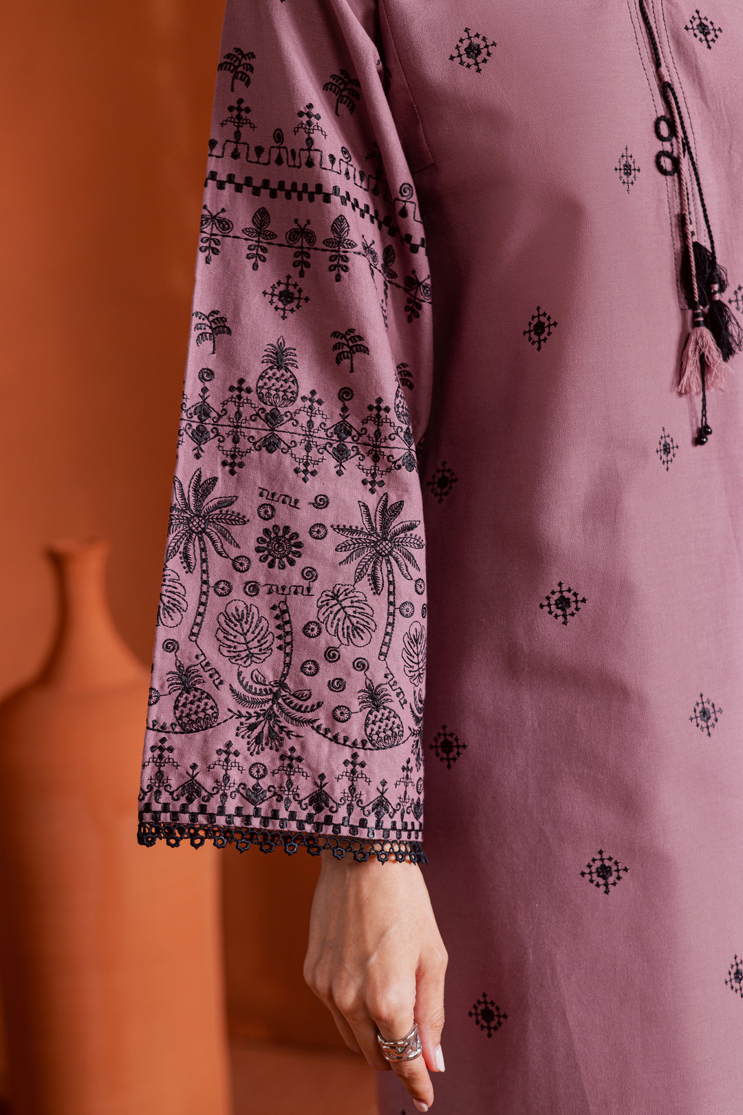 Close-up of black thread embroidery on onion pink khaddar fabric - detailed sleeve design from Batik’s ready-to-wear Pakistani collection, crafted for timeless elegance