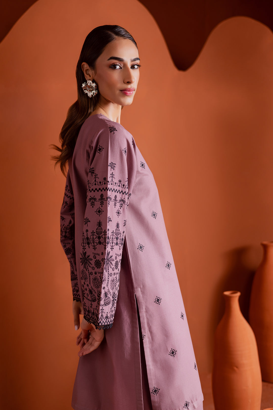 Side view of Pakistani khaddar outfit in onion pink with embroidered sleeves and keyhole neckline featuring tassel ties. Contemporary ethnic wear for women, designed by Batik for the South Asian community in UAE and beyond. Easy delivery across Middle East and global shipping available