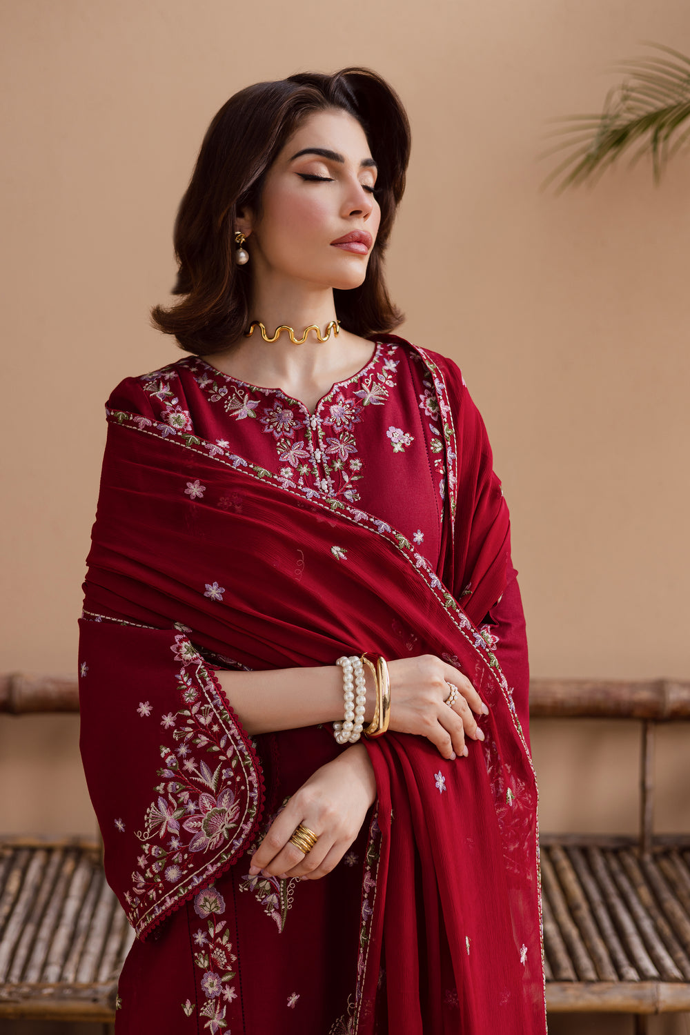 Model in beetroot red embroidered khaddar shirt and trousers set. Traditional South Asian outfit for festive occasions and evening gatherings