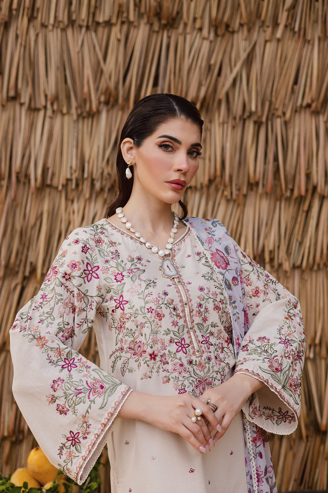 Close-up detail of intricate embroidery and beadwork on beige khaddar fabric, highlighting South Asian artisanal finesse